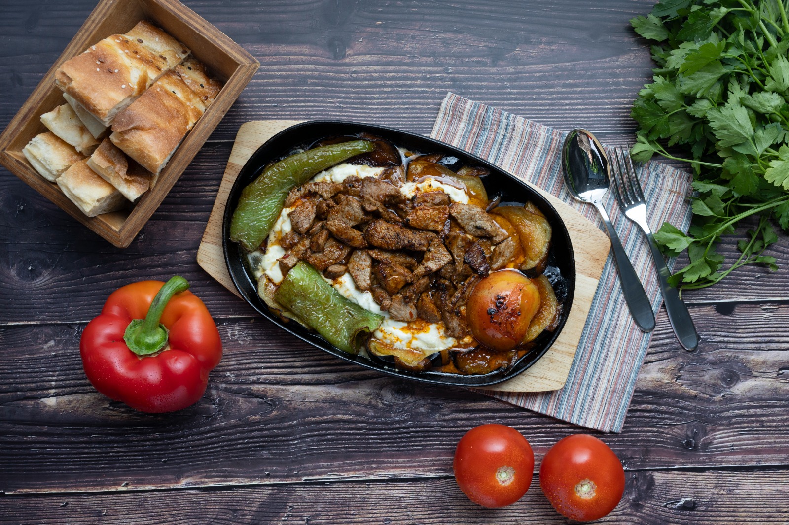 Fleischgericht in der heißen Pfanne mit Joghurt, Paprika und Fladenbrot